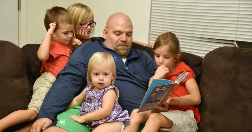 parental involvement ideas include normal things like a father reading to his four children on the couch