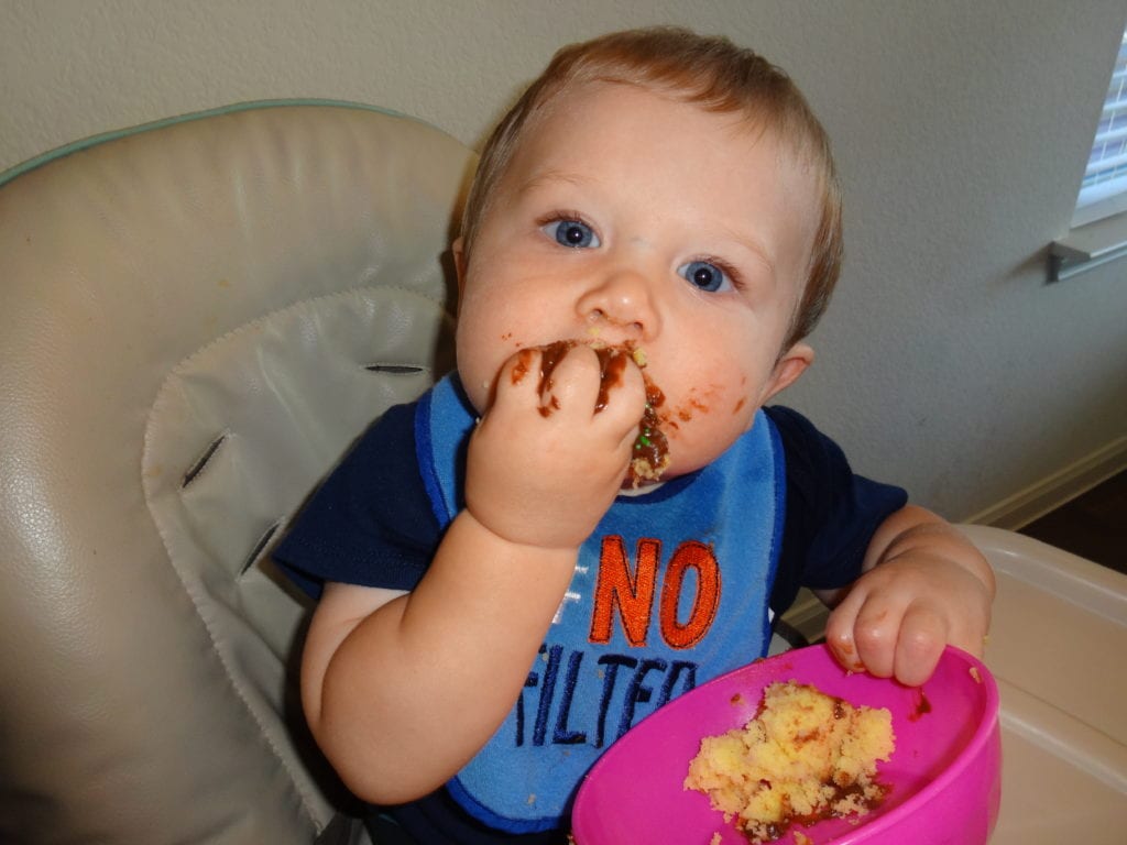 messy baby boy eating food - tips on how to wean to sippy cup