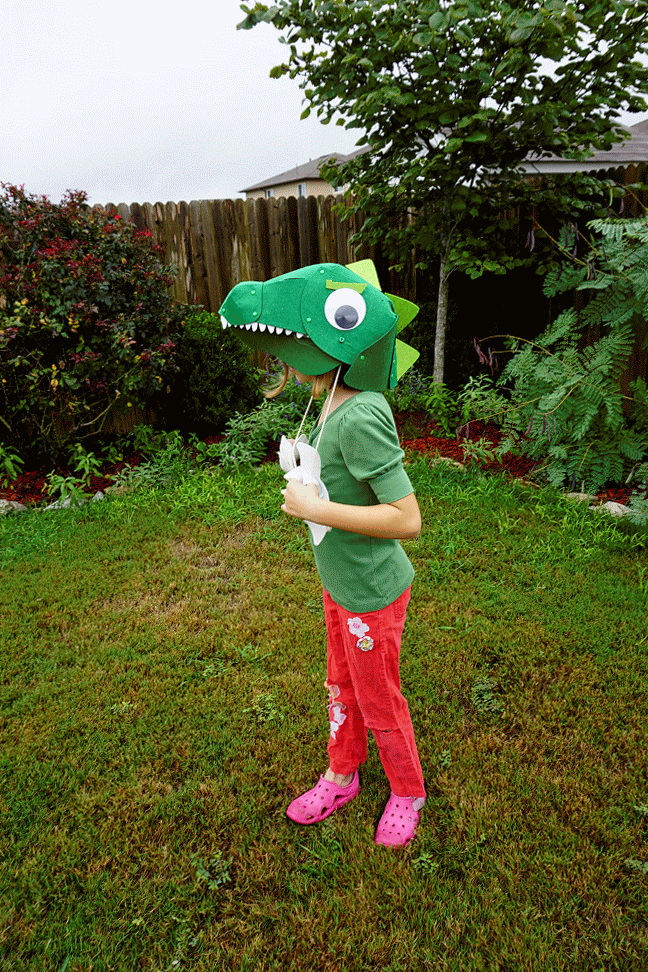 little girls wearing a chomping T Rex head costume 