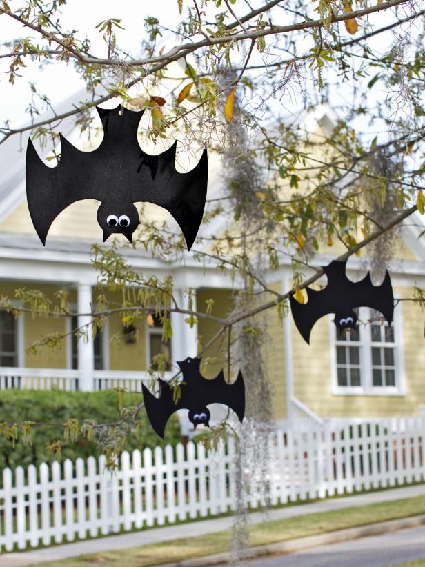 foam bats with googly eyes hanging upside down from tree outside as easy Halloween yard decorations to make