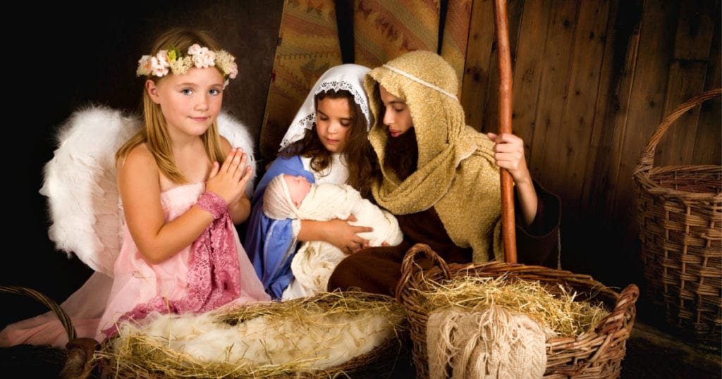 cute little girls acting out nativity scene wearing angel nativity costume, mary nativity costume, and joseph nativity costume