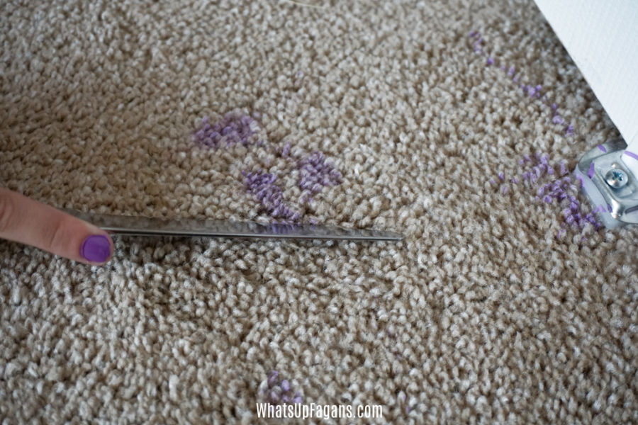 someone attempting to remove acrylic paint from carpet using a butter knife