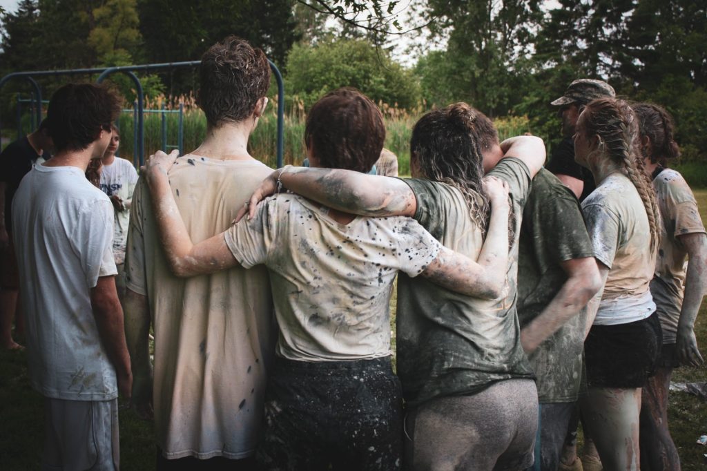 group of hugging, muddy teenage children, showing that the more parental invovlement the more you improve your child's social skills